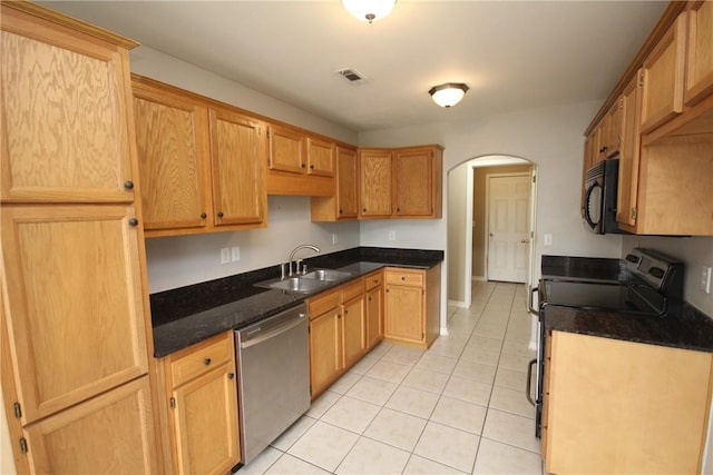 kitchen with stainless steel appliances, a sink, arched walkways, and light tile patterned flooring