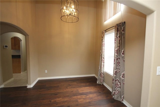 unfurnished dining area with arched walkways, plenty of natural light, and wood finished floors
