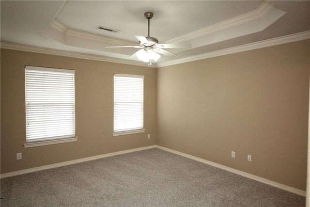 carpeted spare room with a raised ceiling, plenty of natural light, ceiling fan, crown molding, and baseboards
