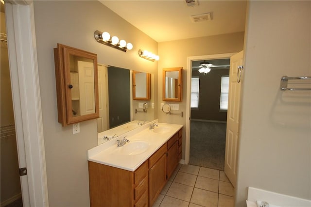 bathroom with tile patterned floors, a walk in closet, double vanity, and a ceiling fan