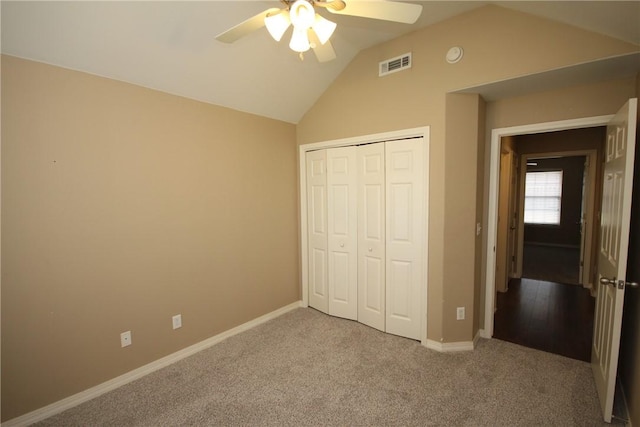 unfurnished bedroom with vaulted ceiling, a closet, carpet floors, baseboards, and ceiling fan