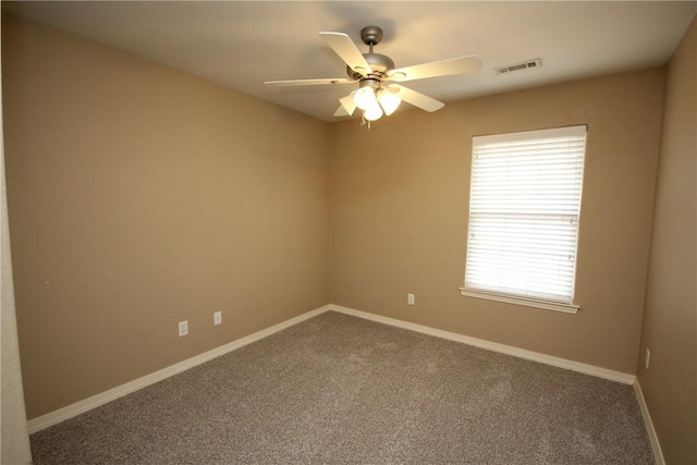 carpeted spare room featuring ceiling fan and baseboards