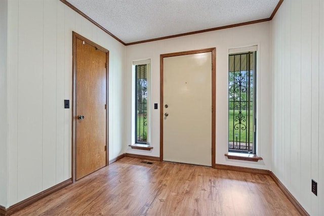 foyer featuring ornamental molding, wood finished floors, a textured ceiling, and baseboards