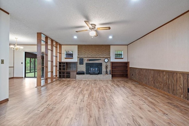 unfurnished living room featuring healthy amount of natural light, ceiling fan, ornamental molding, wood finished floors, and a fireplace