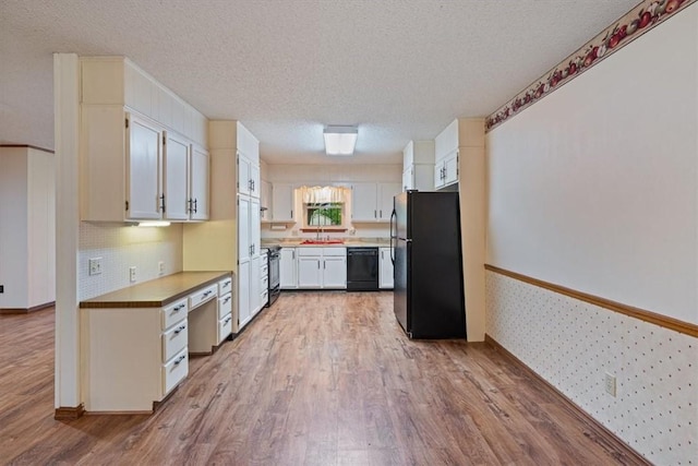 kitchen featuring black appliances, wood finished floors, a textured ceiling, a sink, and light countertops
