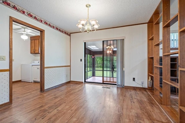 unfurnished dining area featuring washer / clothes dryer, a chandelier, light wood-style flooring, a textured ceiling, and baseboards