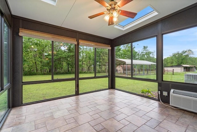 unfurnished sunroom featuring ceiling fan, a skylight, lofted ceiling, and a wall mounted air conditioner