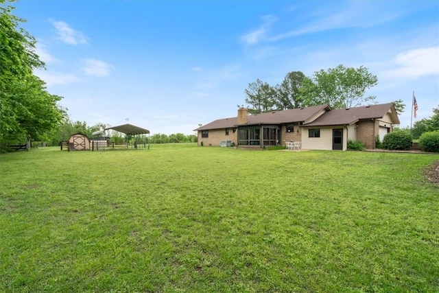 view of grassy yard featuring a detached carport and a sunroom
