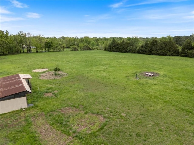 view of grassy yard with a wooded view