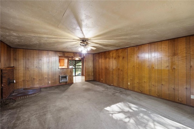 10616 S Liberty Rd, Dardanelle, AR 72834 - empty room with a ceiling fan, wooden walls, heating unit, carpet, and a fireplace