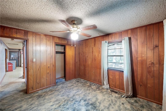 10616 S Liberty Rd, Dardanelle, AR 72834 - unfurnished bedroom with wooden walls, carpet floors, a closet, a ceiling fan, and a textured ceiling