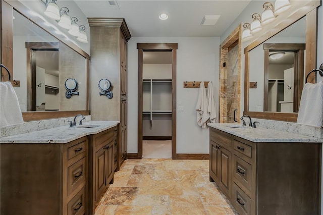7 W Colonial Dr, Rogers, AR 72758 - bathroom featuring baseboards, two vanities, a walk in closet, and stone finish flooring