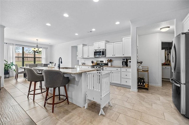 kitchen featuring stainless steel appliances, a sink, white cabinets, a chandelier, and recessed lighting
