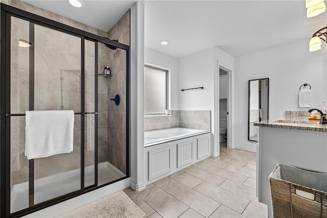bathroom featuring toilet, a stall shower, a garden tub, tile patterned floors, and vanity