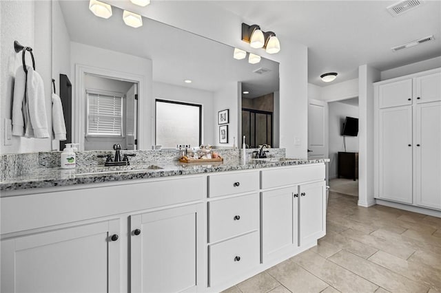 bathroom featuring a stall shower, double vanity, and tile patterned floors