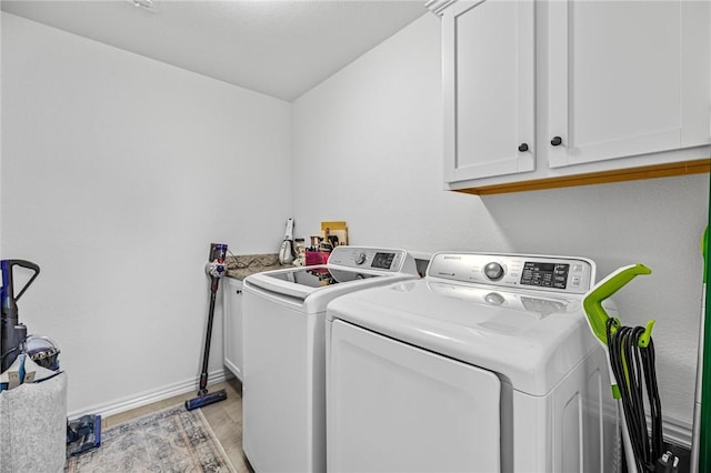 clothes washing area featuring cabinet space, independent washer and dryer, baseboards, and light wood-style floors