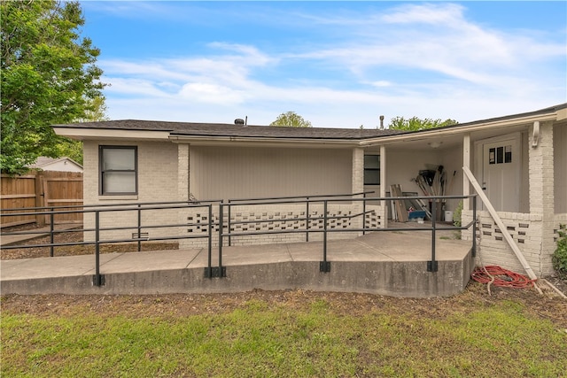 back of property featuring brick siding, fence, and a patio