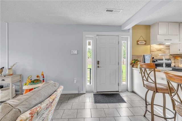 entryway with a textured ceiling and light tile patterned floors