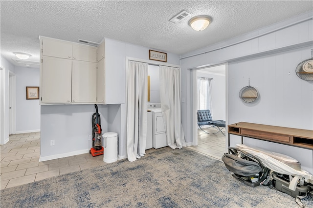 misc room with light tile patterned floors, a textured ceiling, and washer / dryer