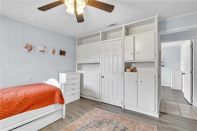 bedroom with light wood-type flooring, a textured ceiling, and ceiling fan