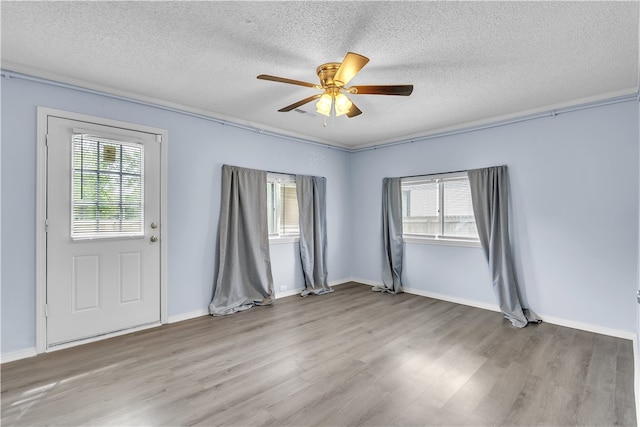 spare room featuring a textured ceiling, wood finished floors, a ceiling fan, and baseboards