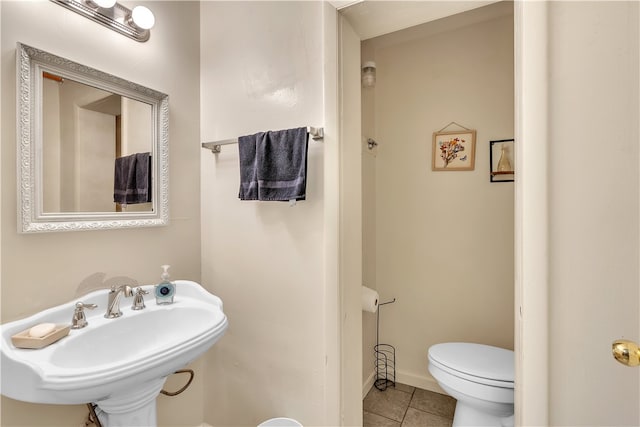 bathroom featuring tile patterned flooring, toilet, and a sink