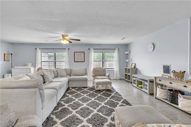 living area with ceiling fan, a textured ceiling, and light tile patterned floors