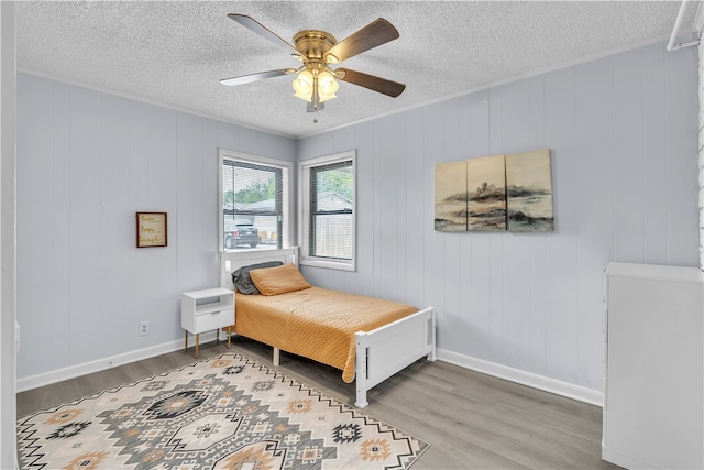 bedroom with wood finished floors, ceiling fan, a textured ceiling, and baseboards