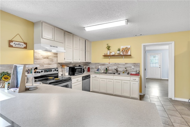 kitchen featuring appliances with stainless steel finishes, a sink, tasteful backsplash, a textured ceiling, and light tile patterned floors