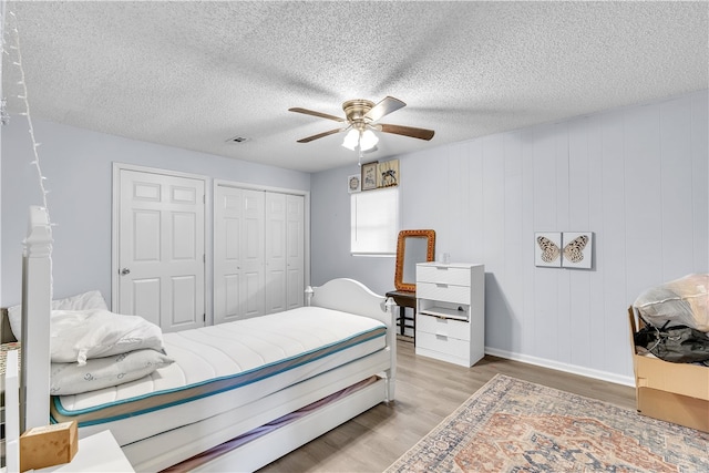bedroom with wood finished floors, a closet, a ceiling fan, a textured ceiling, and baseboards