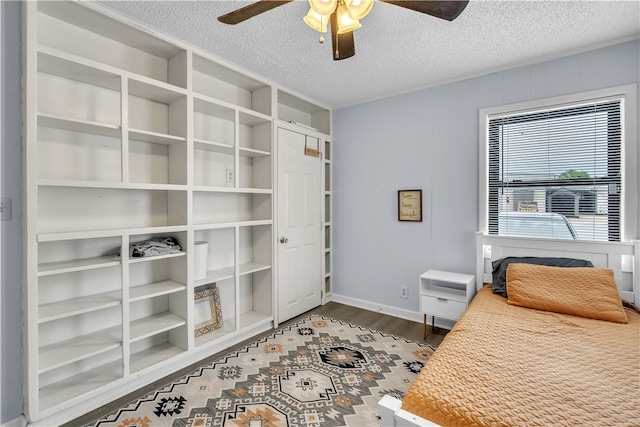 bedroom with dark wood finished floors, a textured ceiling, baseboards, and ceiling fan