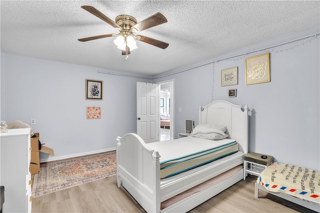 bedroom featuring a textured ceiling, light wood-style flooring, and a ceiling fan