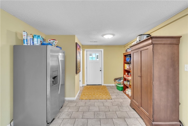 clothes washing area featuring a textured ceiling, light tile patterned floors, and baseboards
