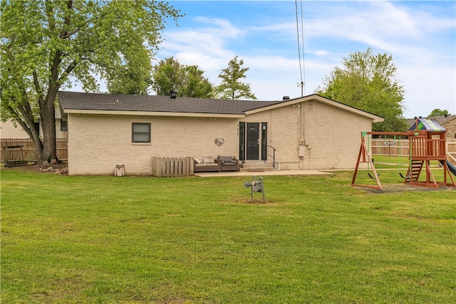 back of house featuring an outdoor living space, a playground, a patio, and brick siding