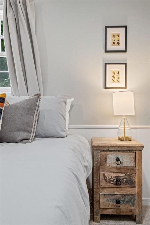carpeted bedroom featuring a wainscoted wall