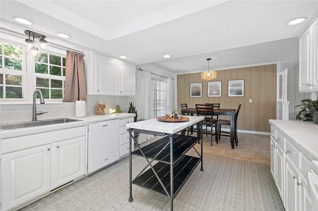 kitchen with dishwasher, a sink, light countertops, white cabinetry, and recessed lighting