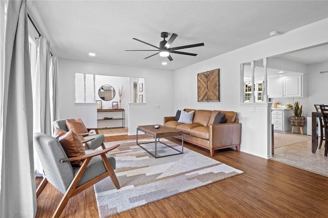 living room featuring ceiling fan, wood finished floors, a textured ceiling, baseboards, and recessed lighting
