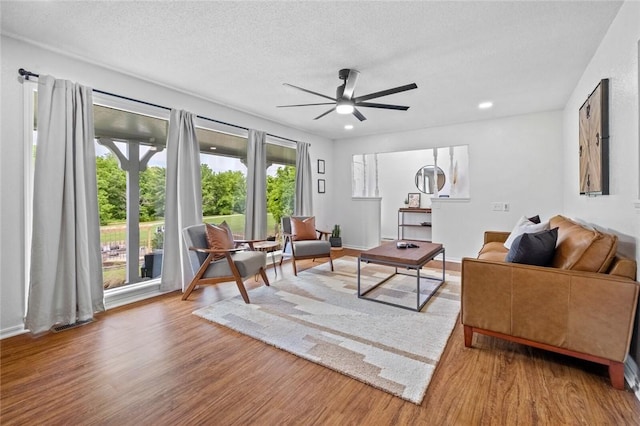 living room featuring wood finished floors, a ceiling fan, and a textured ceiling