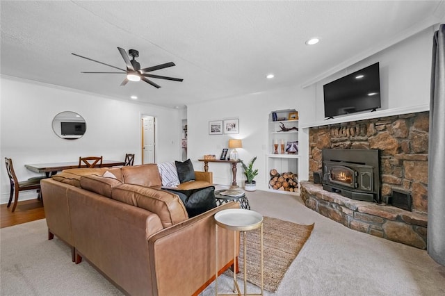living room featuring carpet, a wood stove, ceiling fan, recessed lighting, and built in features