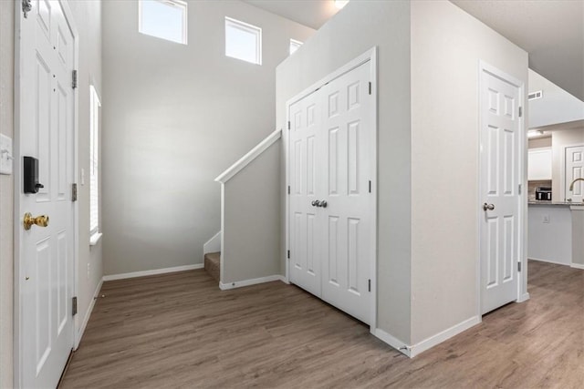 foyer entrance with light wood-style flooring, stairway, and baseboards