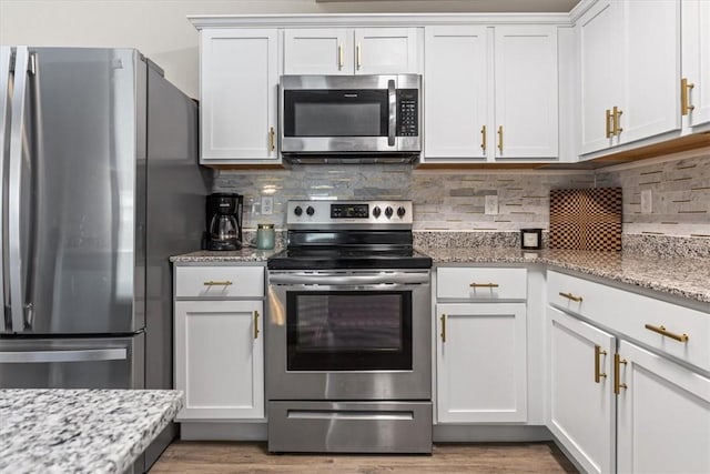 kitchen with stainless steel appliances, wood finished floors, white cabinets, and backsplash