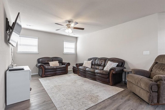 living area featuring a ceiling fan, wood finished floors, and baseboards