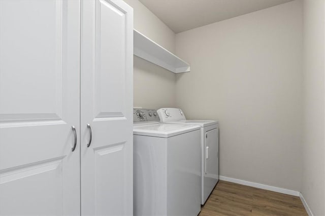 laundry room featuring separate washer and dryer, light wood-type flooring, and baseboards