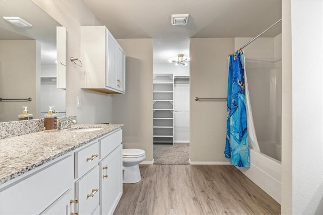 bathroom featuring wood finished floors, toilet, vanity, baseboards, and shower / tub combo with curtain