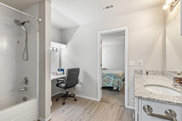 full bathroom featuring wood finished floors, washtub / shower combination, vanity, baseboards, and ensuite bath
