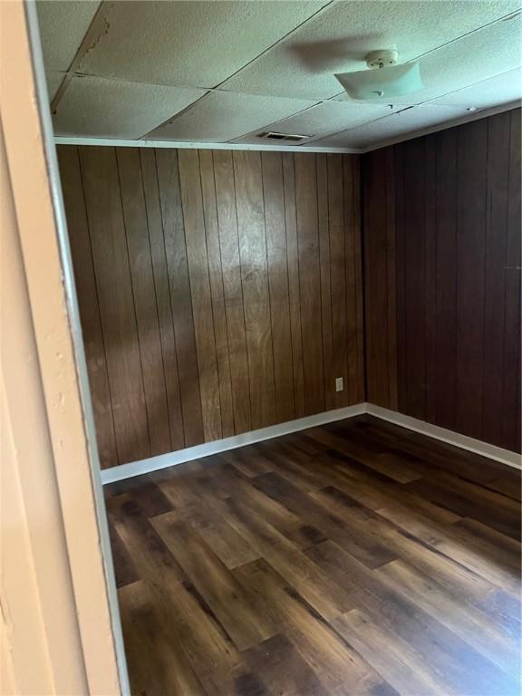 spare room featuring dark wood-type flooring and wood walls