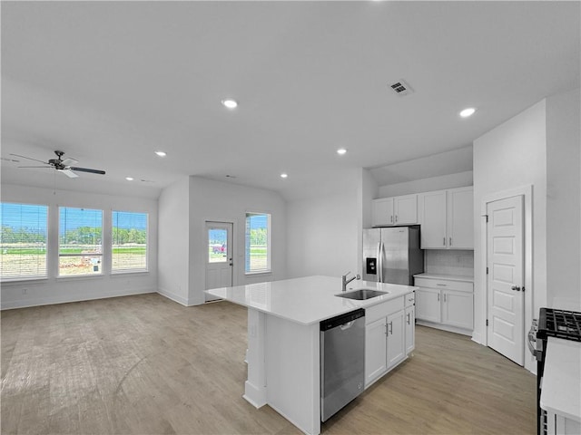 kitchen featuring stainless steel appliances, a sink, light wood-style flooring, light countertops, and white cabinetry