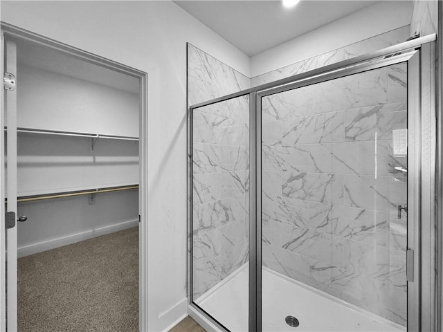 bathroom featuring a marble finish shower and a spacious closet