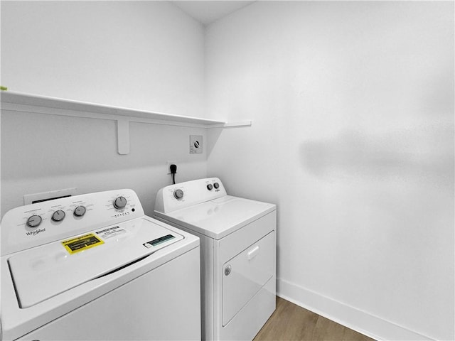 clothes washing area featuring washer and dryer, wood finished floors, and baseboards