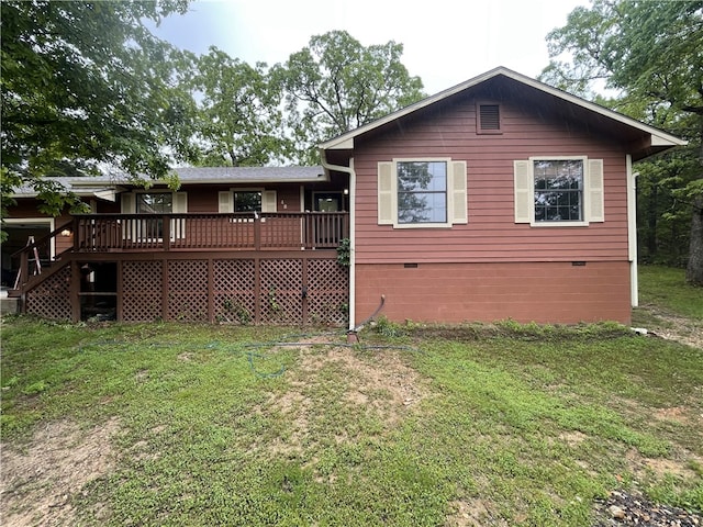 rear view of property with crawl space, a deck, and a lawn
